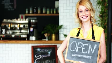 portrait of waitress standing with open sign board