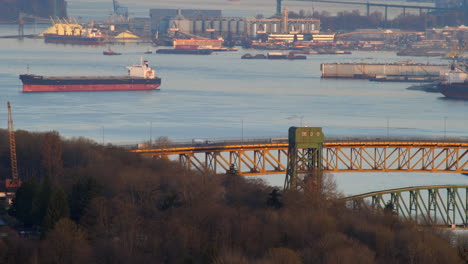 the big bridge in vancouver canada suspended above the peaceful seawater surrounded with boats docked in the shore - wide shot