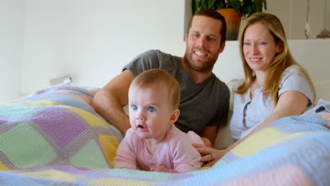 front view of mid adult caucasian parents playing with baby on bed in a comfortable home 4k