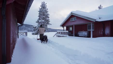 Hombre-Limpiando-El-Patio-Trasero-En-Nieve-Profunda-Usando-Una-Pala-De-Trineo-En-Indre-Fosen,-Noruega---Ancho