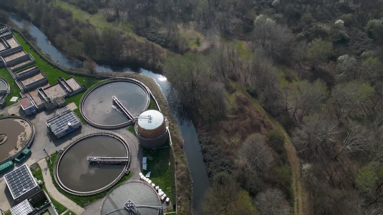 Aerial view of wastewater treatment facility in Milan, Italy with circular tanks and industrial basins. Infrastructure combines water purification and renewable energy production using biogas systems