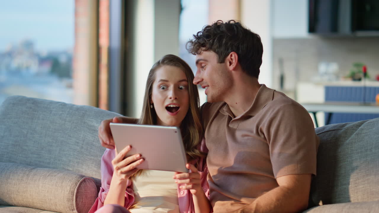 Married couple looking tablet sitting sofa cozy home closeup. Smiling man