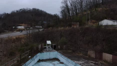 aerial drone footage pushing in over an overgrown wave pool in an abandoned water park