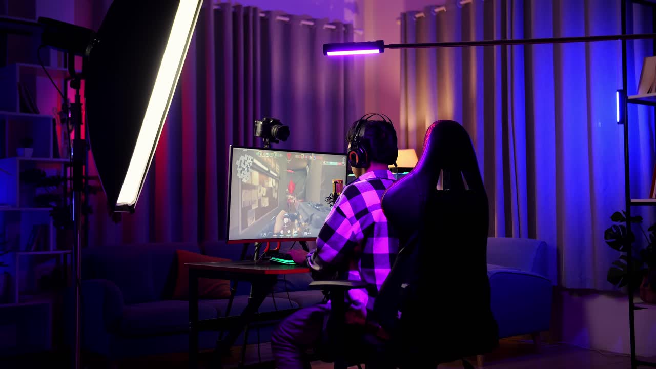 vista trasera de un niño asiático que grita gol celebrando el juego ganador a través de la red en una computadora personal. videojuego de transmisión en vivo, escritorio iluminado por luz de tira led rgb