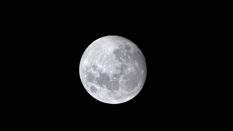 Lua cheia se pondo no céu noturno, superfície iluminada com crateras detalhadas.