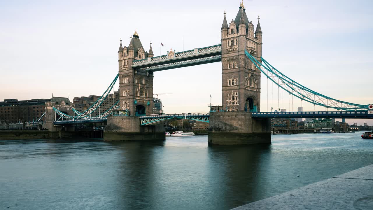 Trafik kører over Tower Bridge, mens solen går ned i baggrunden.