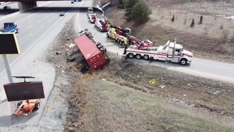 gran camión semi rojo volcado en la autopista en la rampa, los camiones de remolque intentan tirarlo hacia atrás