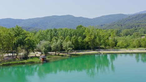 Pull-out-aerial-view-from-the-shores-of-Lake-Banyoles-across-the-water