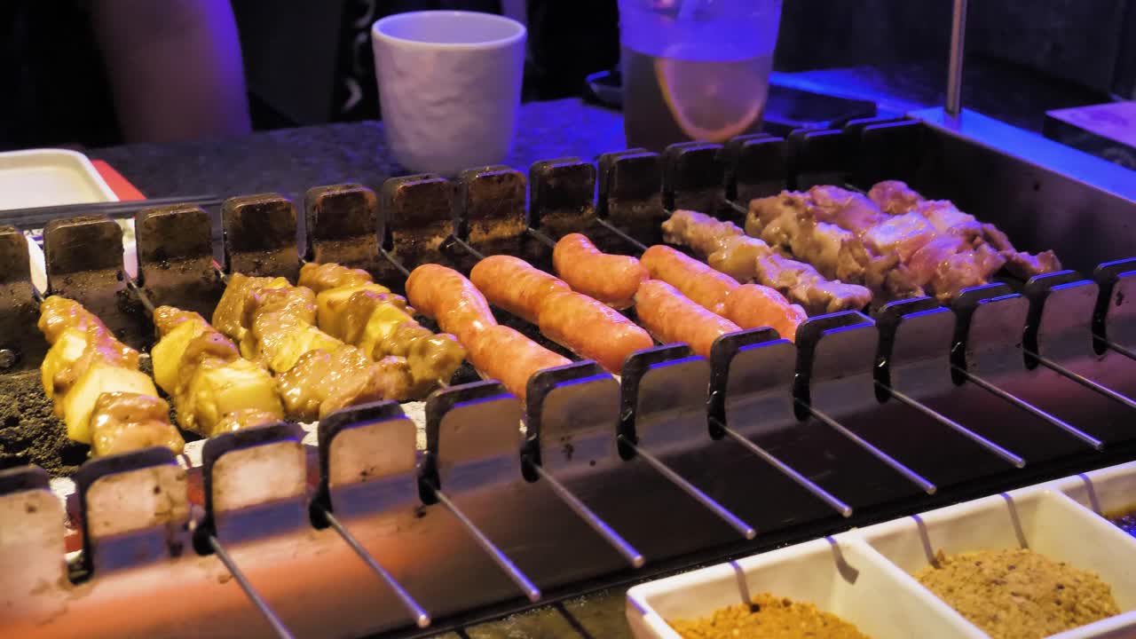 parrilla de barbacoa, rodar pedazos de carne en soportes metálicos, secuencia de video capturada en el restaurante de barbacoa china de chengdu, preparación de alimentos y concepto de amantes de la comida