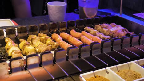 Barbecue-grill,-rolling-peaces-of-meat-onto-metal-holders,-video-sequence-captured-at-Chengdu-Chinese-BBQ-restaurant,-food-preparation-and-food-lovers-concept