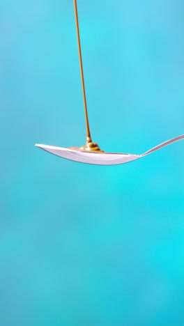 vertical video of melted chocolate being poured onto spoon and overflowing against blue coloured background with copy space 1