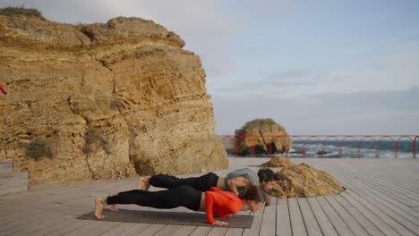 pareja practicando yoga al aire libre junto al océano