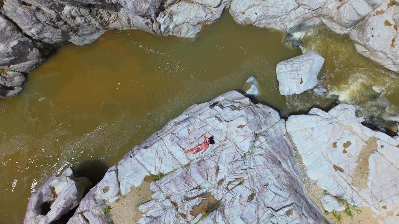 Vista a volo d'uccello di una ragazza che prende il sole sulla roccia calcarea scolpita del Cañón Blanco di Porto Rico, ripresa con drone