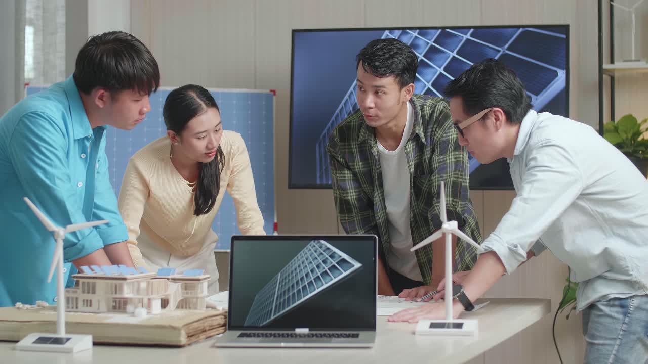 테이블 위의 노트북은 아시아 엔지니어 그룹이 사무실에서 블루프린트 작업에 대해 논의하는 동안 태양전지를 보여줍니다.
