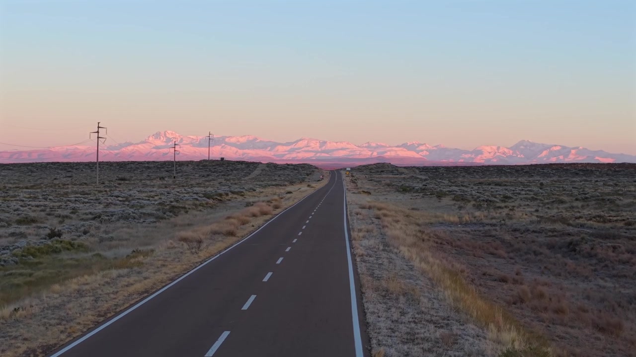 Dron aéreo sigue la recta carretera RN 144 hacia los Andes rosados resplandecientes al amanecer.