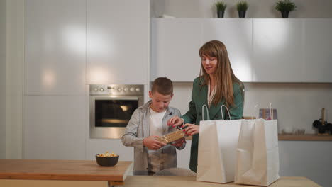 schoolboy helps mom taking waffles, cookies and cupcakes