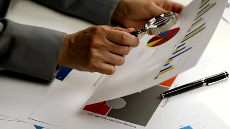 woman examining business graph with magnifier glass in hand