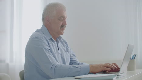 adult man is typing on laptop keyboard in his office during working day sending messages to colleagues partners and employees