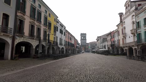 charming pastel buildings and tower-lined cobblestone street in picturesque este, italy.