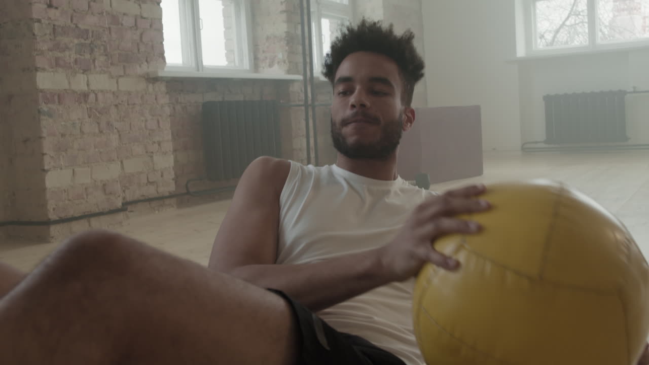 Black Sportsman Doing Side Crunches With Weight Ball