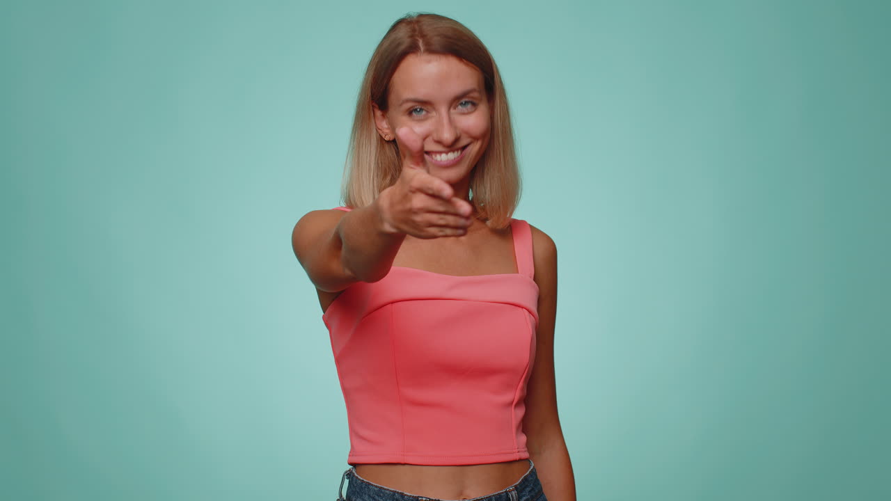 mujer amigable extendiendo la mano a la cámara, ofreciendo un apretón de mano, saludando con una sonrisa amable, bienvenida
