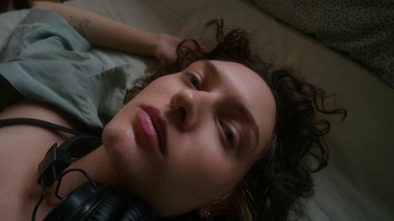 mujer acostada en la cama con auriculares