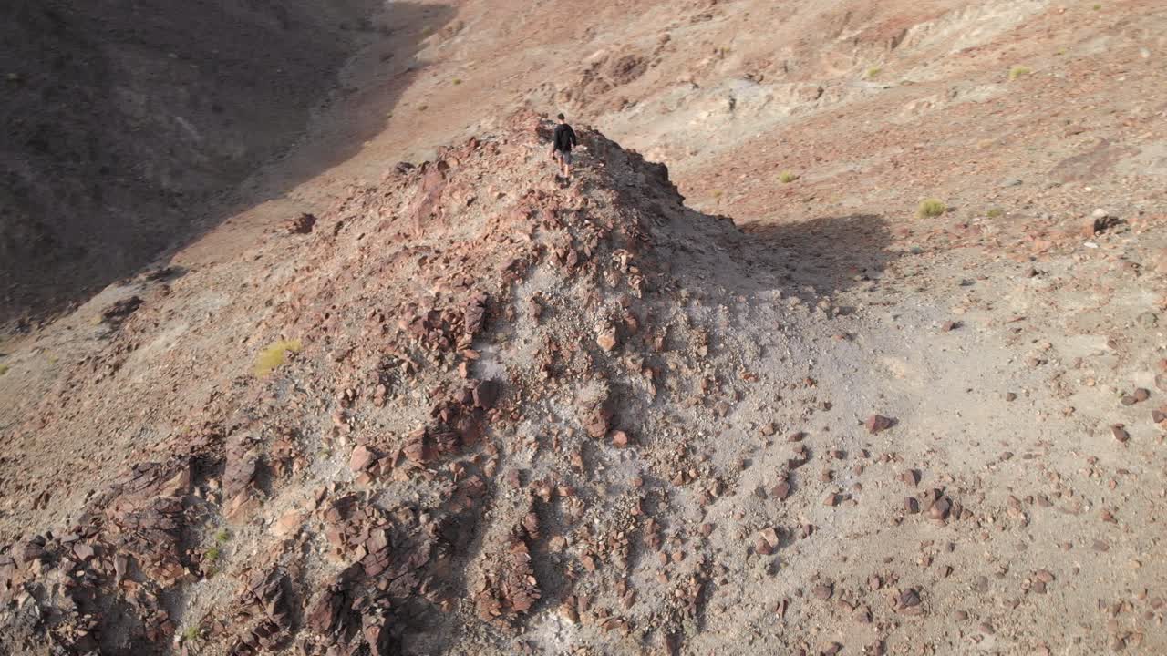 아랍 에미레이트 하타의 바위산 정상을 걷는 젊은 남성의 드론에서 원형 공중 서사시 촬영