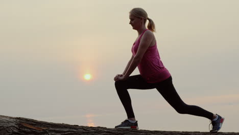 Active-Middle-Aged-Woman-Is-Training-Against-The-Backdrop-Of-The-Sea-And-The-Rising-Sun