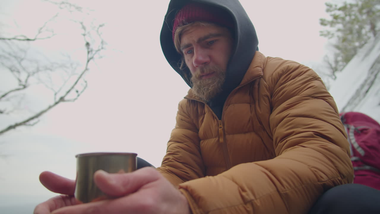 Man Warming Up with Hot Tea at Campsite in Mountains