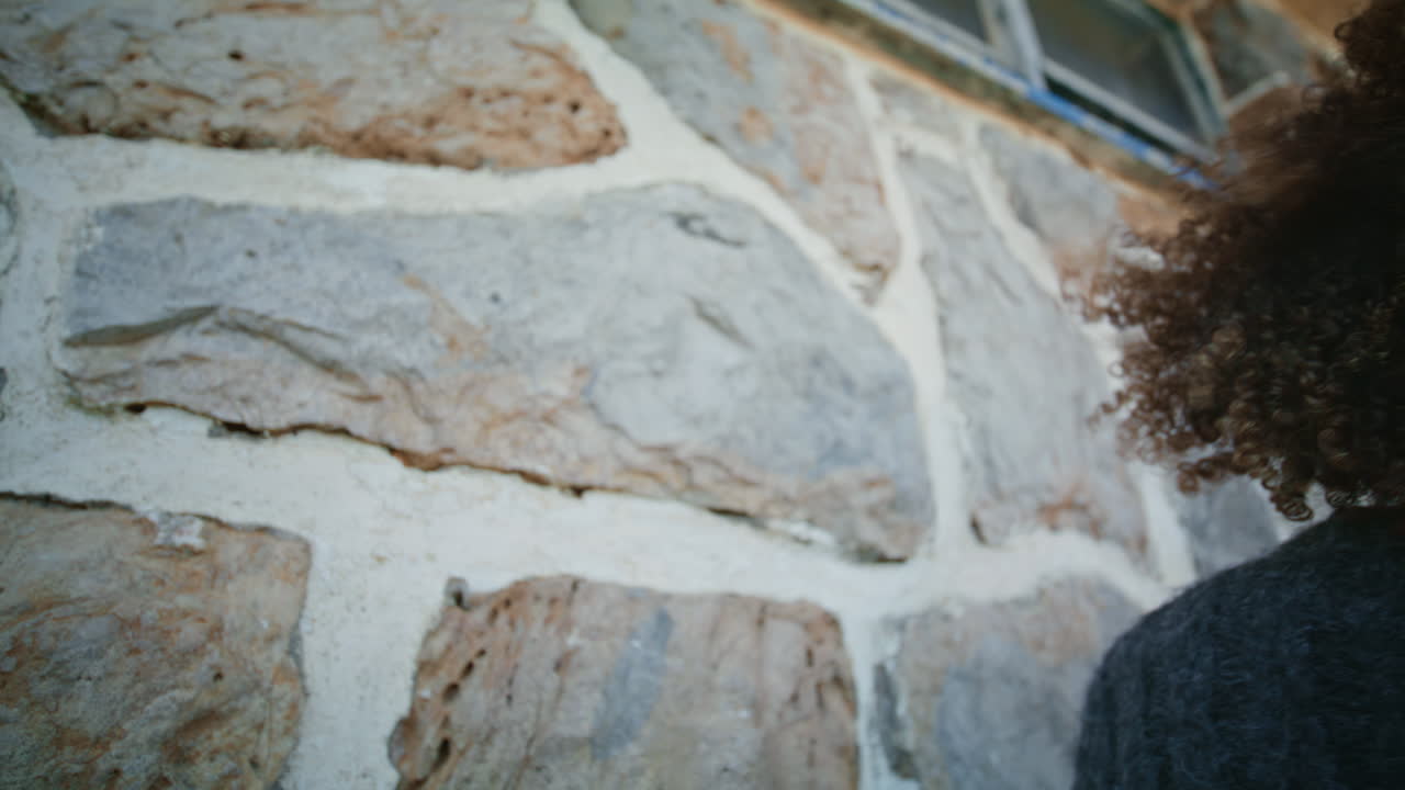 Donna pensierosa che guarda in lontananza in piedi davanti a un muro, primo piano. Ragazza autunnale.