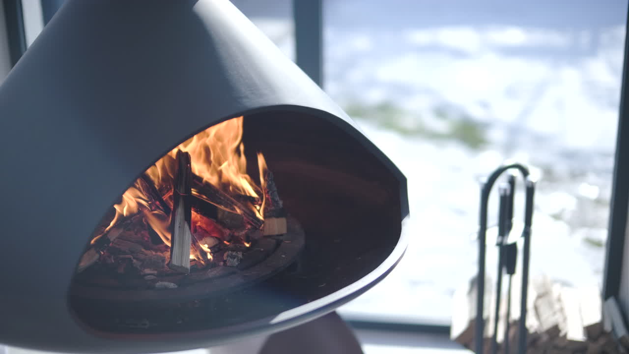 Modern Fireplace with Burning Wood and Snowy Winter View
