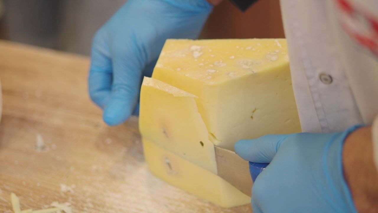 Chef cortando un gran bloque de queso en una cocina