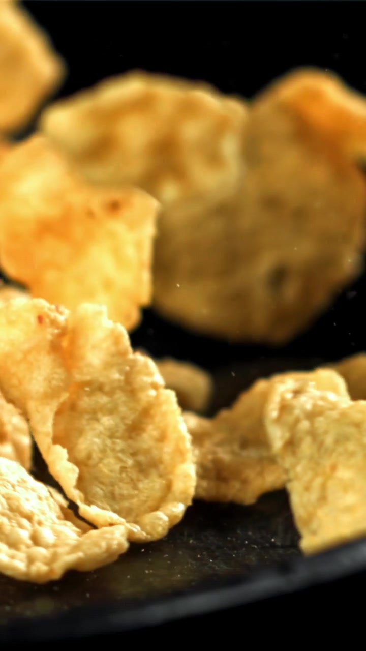 Cornflakes dorati che cadono al rallentatore su uno sfondo nero