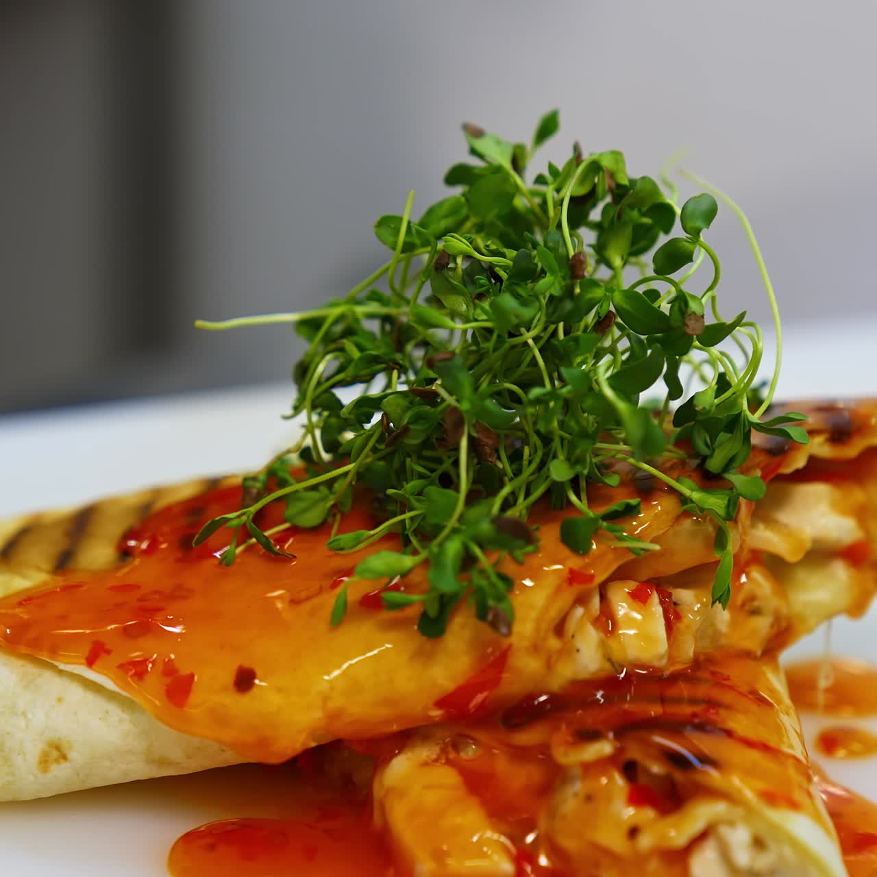 Delicious pita poured with sauce. Cook decorates a dish with green sprouts. Before serving a meal, the chef of the restaurant completes the decoration.Close-up