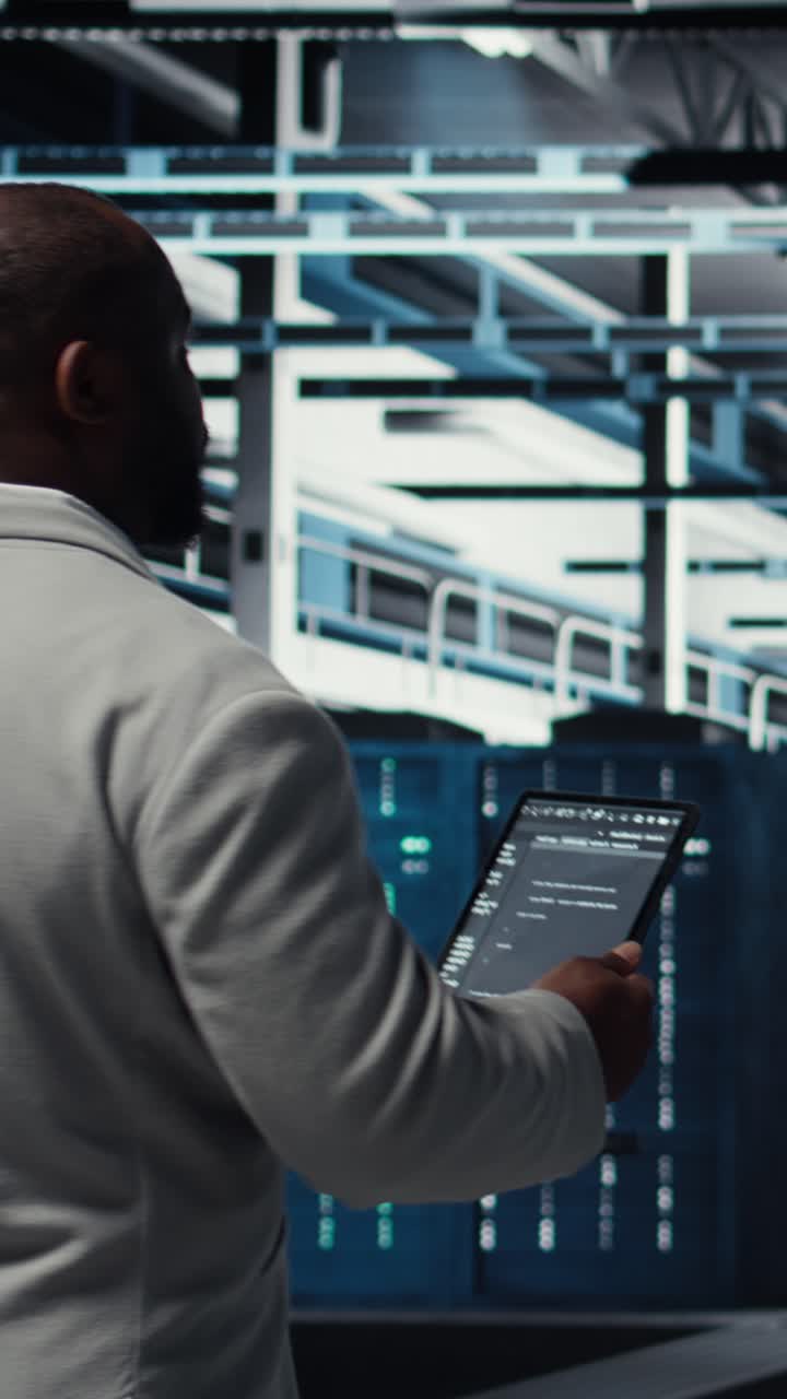 Vertical video Programmers walking in data center coding, doing optimizations using tablet