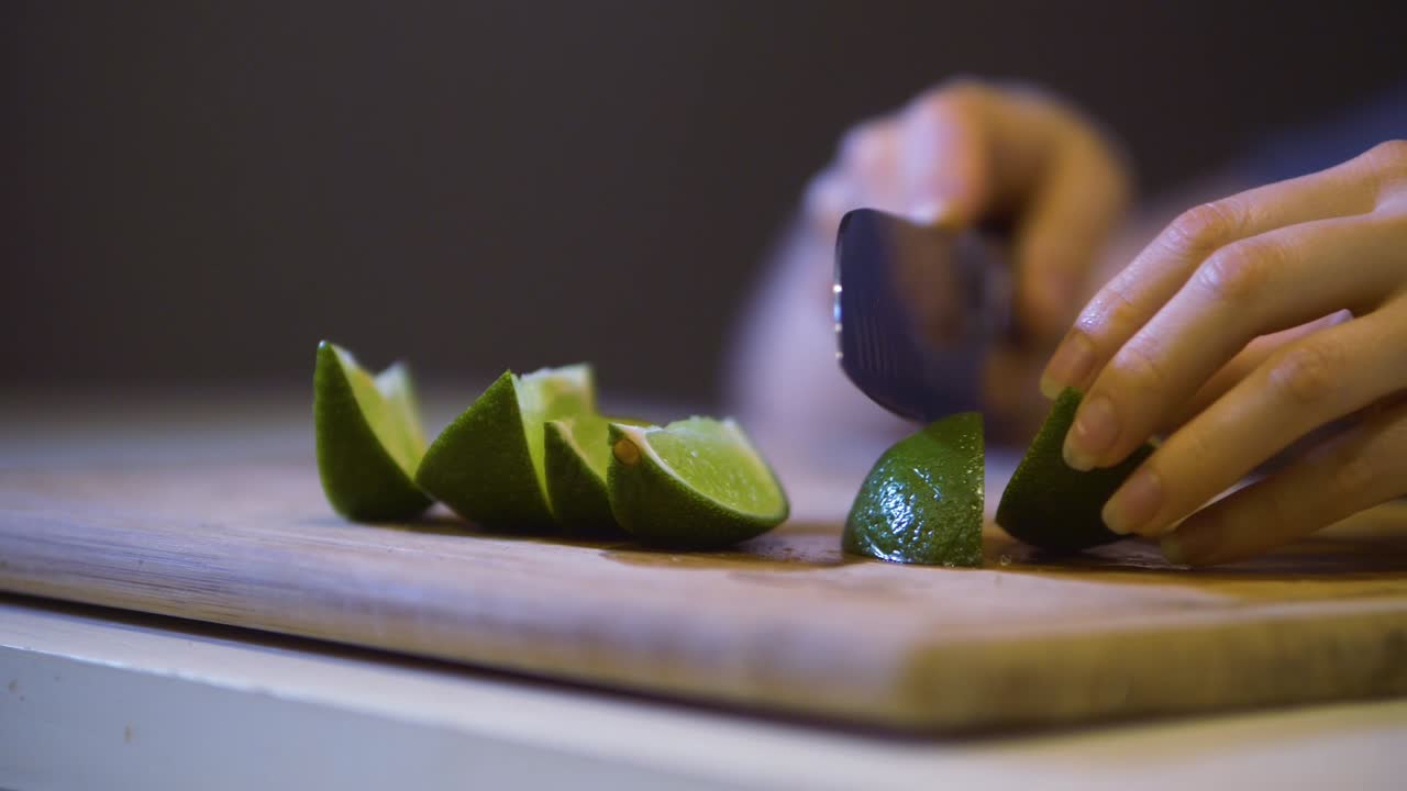 woman's hand cuts lime into slices on a cutting board, slow motion