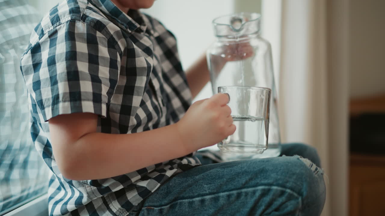 Child pouring water from a pitcher into a glass