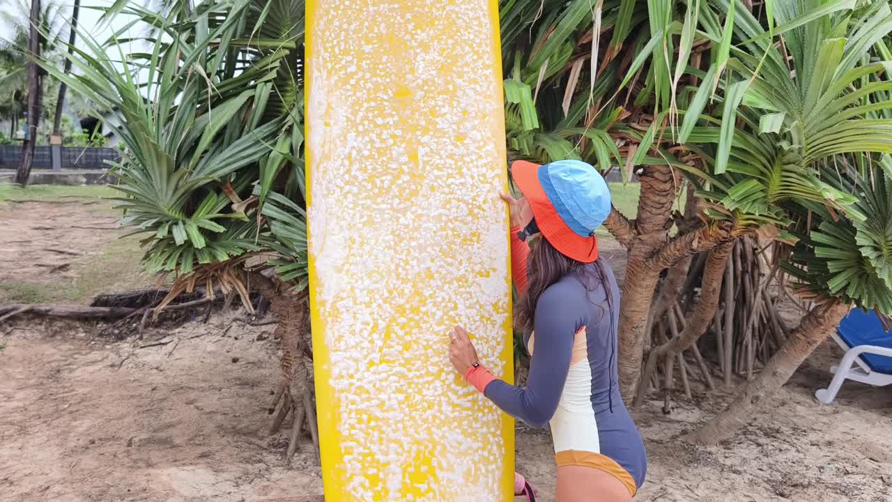 mujer examinando la tabla de surf en la playa