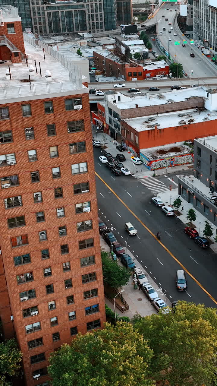 Urban landscape with blocks of flats and roads. Green areas on the tops of the houses. Vertical video