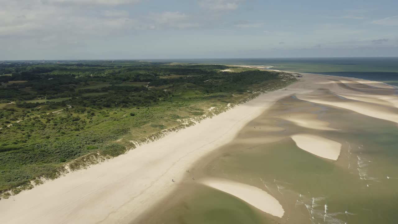 toma aérea volando sobre dunas verdes, una playa blanca, dunas de arena y el mar en un hermoso día soleado