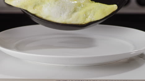 placing an omelette onto a white plate