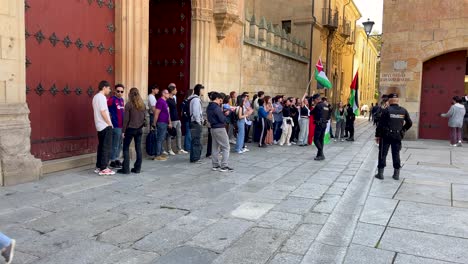filming of a student demonstration for palestine on the façade of the university's higher school, they carry flags and banners, police appear watching and journalists with cameras appear