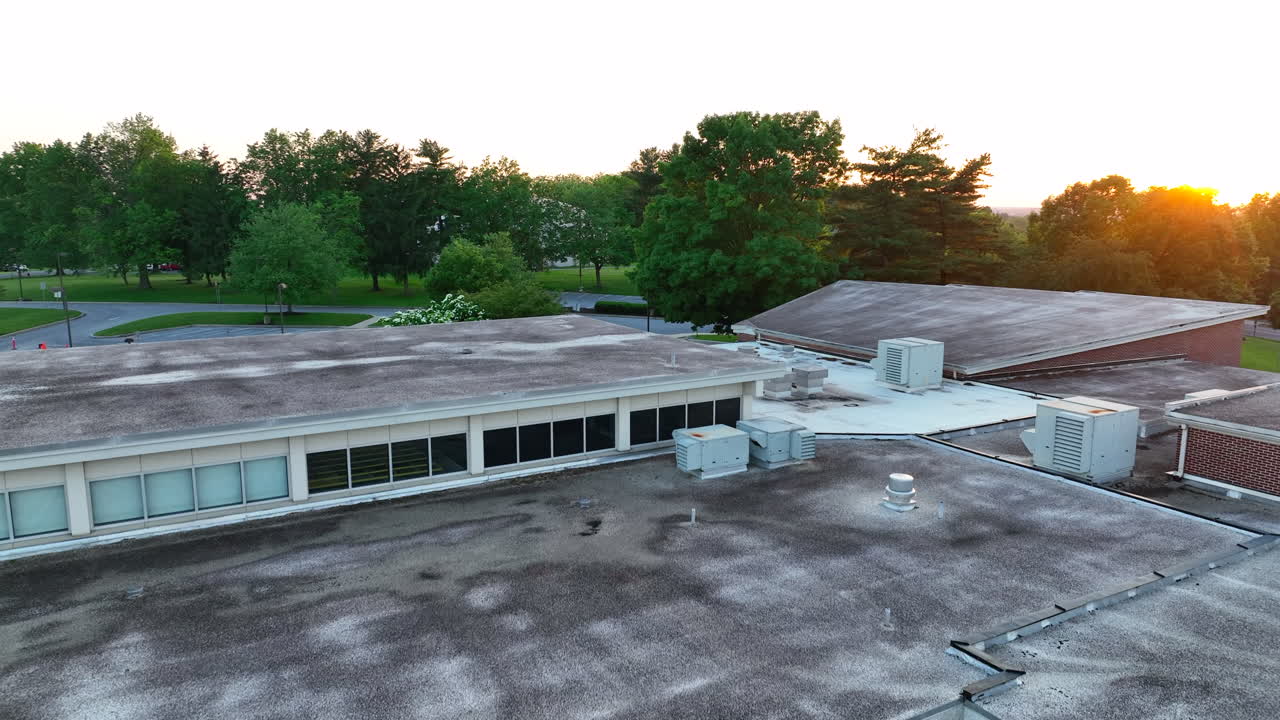 Aerial rising shot of elementary school classrooms. Reveals beautiful sunset over blooming trees
