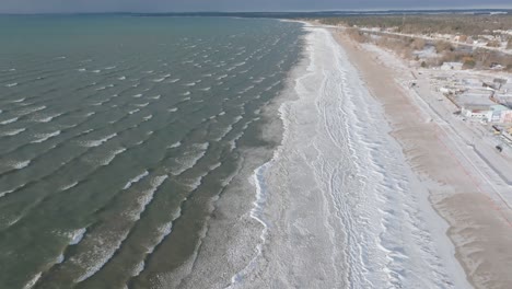 una suave costa con olas rítmicas, comunidad costera visible, atmósfera serena, vista aérea