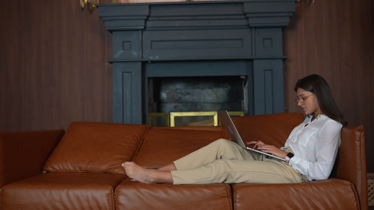 mujer trabajando en una computadora portátil en un sofá en casa