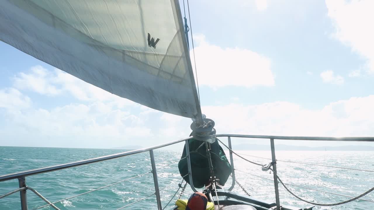 Bow of a sailboat sailing into the clear blue horizon.