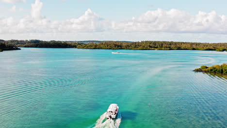 seguimiento aéreo de un pequeño bote navegando a lo largo del río azul turquesa