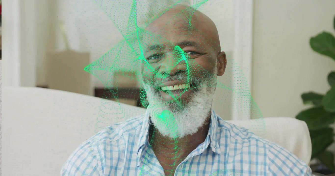 Senior man sitting on sofa smiling and activating swirling green mesh showing data energy