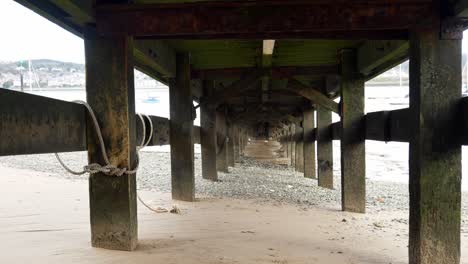 debajo de la madera costera de madera embarcadero de pesca turismo playa con marea baja derecha dolly shot