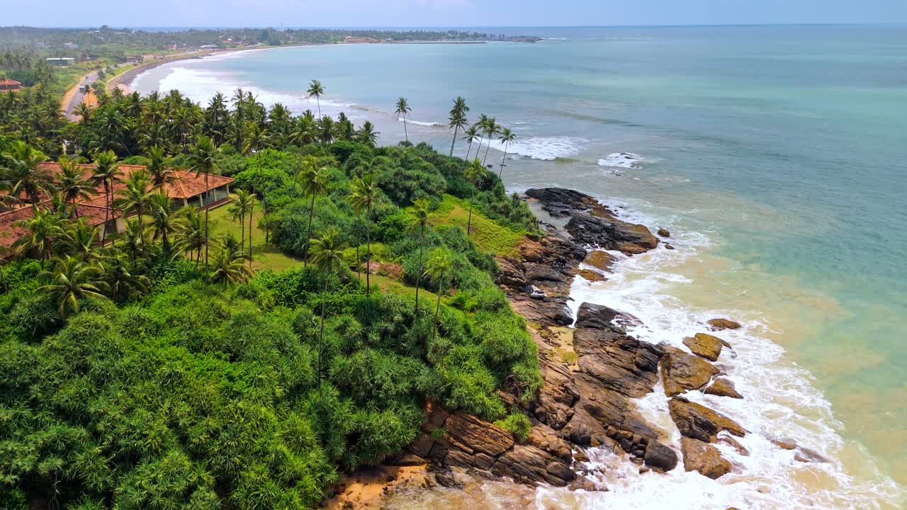 A breathtaking aerial drone shot of SK Town Surf Beach in Weligama, Sri Lanka, where lush jungle meets the ocean.